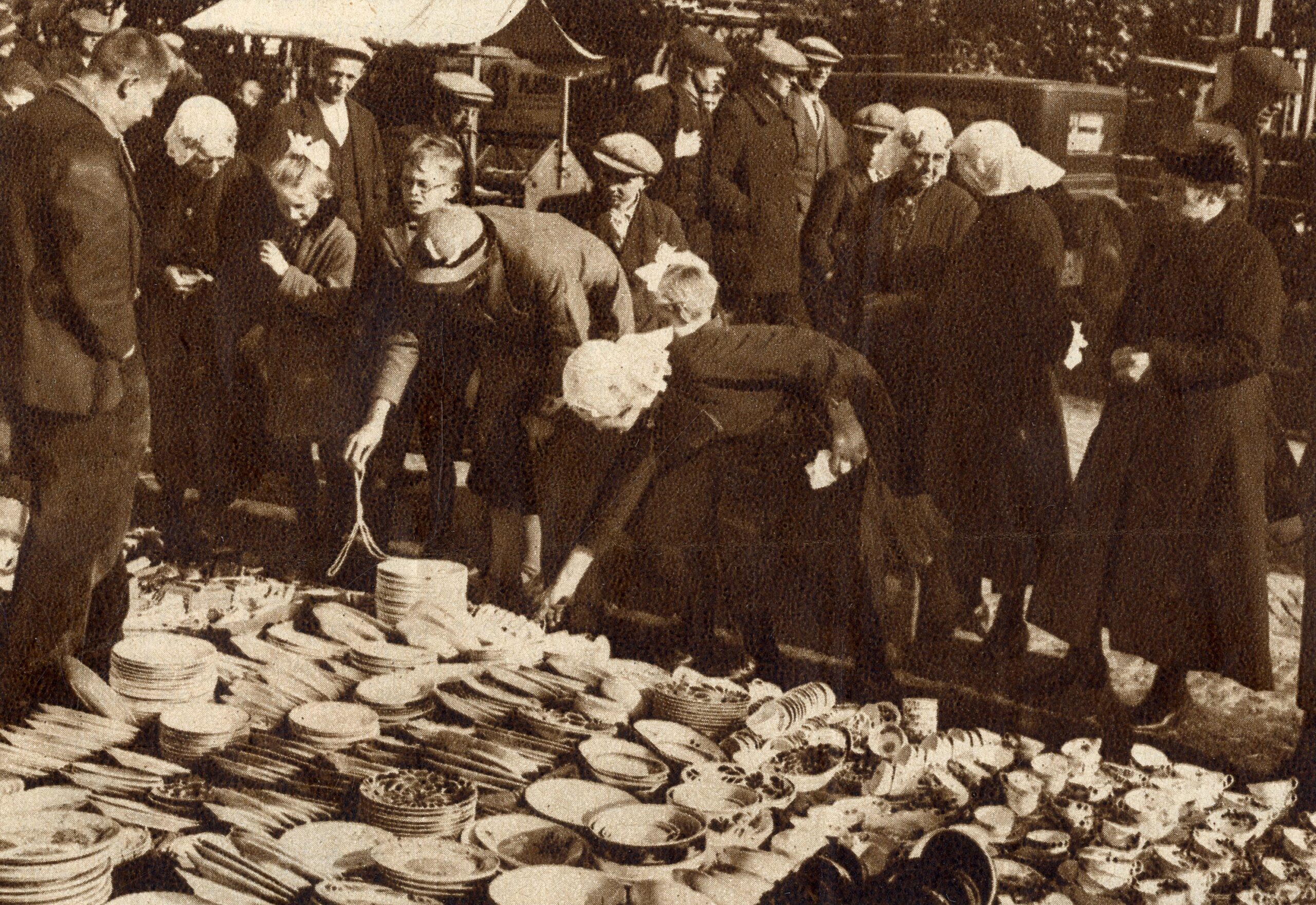 Drentse huisvrouwen in klederdracht kijken bij het uitgestalde servies op de markt te Dwingeloo 1935